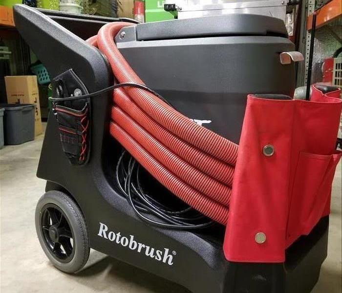 Black and grey vacuum system with red hoses wrapped around it